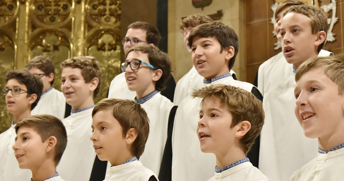 Montserrat Boy Choir members in cassocks singing