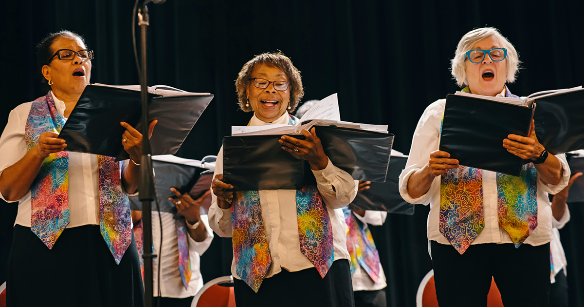 Three adult Vintage Voices members holding black folders and singing. Photo Credit: Adja Gildersleve