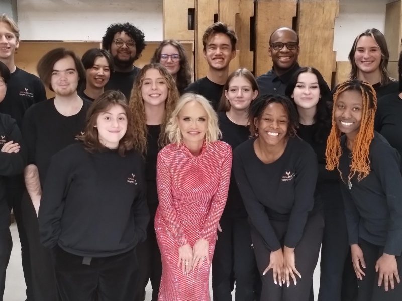 VocalEssence Singers wearing black pose with Kristin Chenoweth in center wearing a pink dress. Photo Credit: Rhiannon Fiskradatz