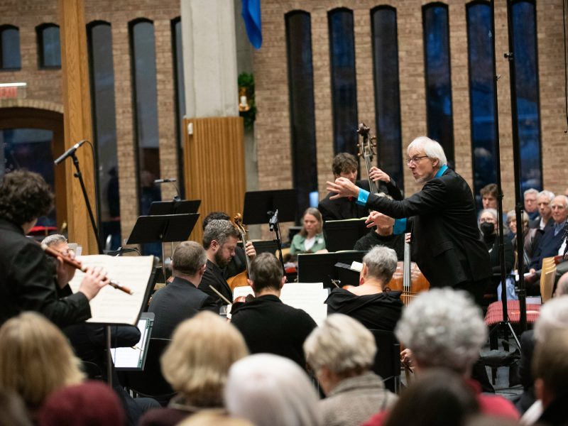 Person conducting orchestra members.