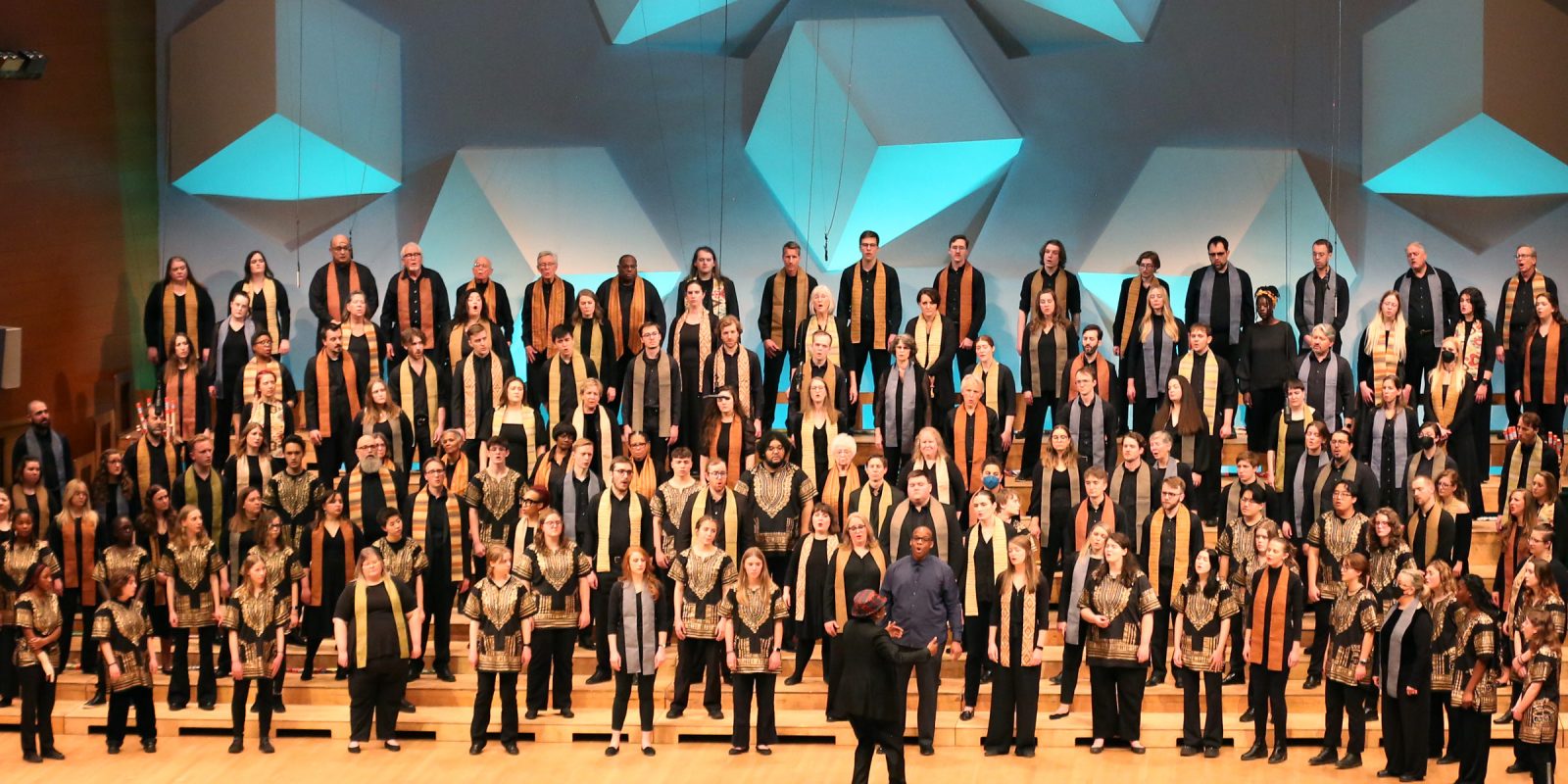 VocalEssence singers wearing black and multicolored stoles perform on stage for the annual WITNESS concert. Photo Credit: Kyndell Harkness