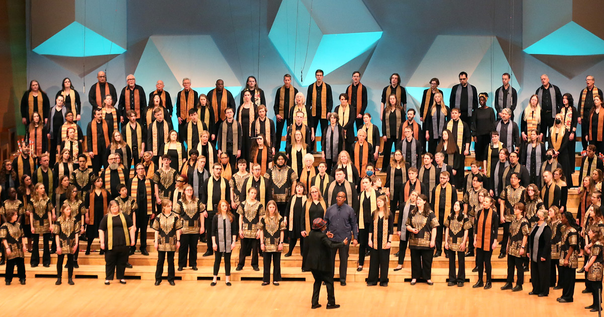 VocalEssence singers wearing black and multicolored stoles perform on stage for the annual WITNESS concert. Photo Credit: Kyndell Harkness