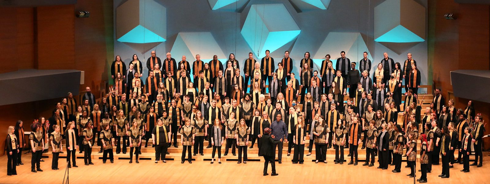 VocalEssence singers wearing black and multicolored stoles perform on stage for the annual WITNESS concert. Photo Credit: Kyndell Harkness