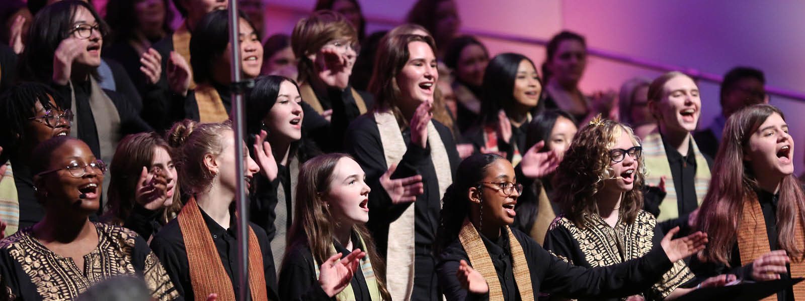 VocalEssence Singers Of This Age wearing black and multicolored stoles perform on stage for the annual WITNESS concert. Photo Credit: Kyndell Harkness