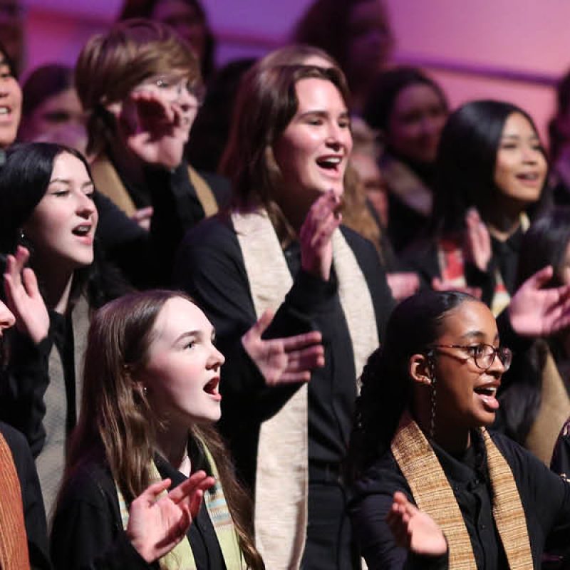 VocalEssence Singers Of This Age wearing black and multicolored stoles perform on stage for the annual WITNESS concert. Photo Credit: Kyndell Harkness