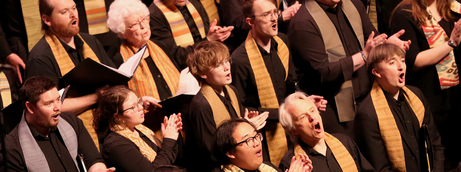VocalEssence singers wearing black and multicolored stoles singing. Photo Credit: Kyndell Harkness